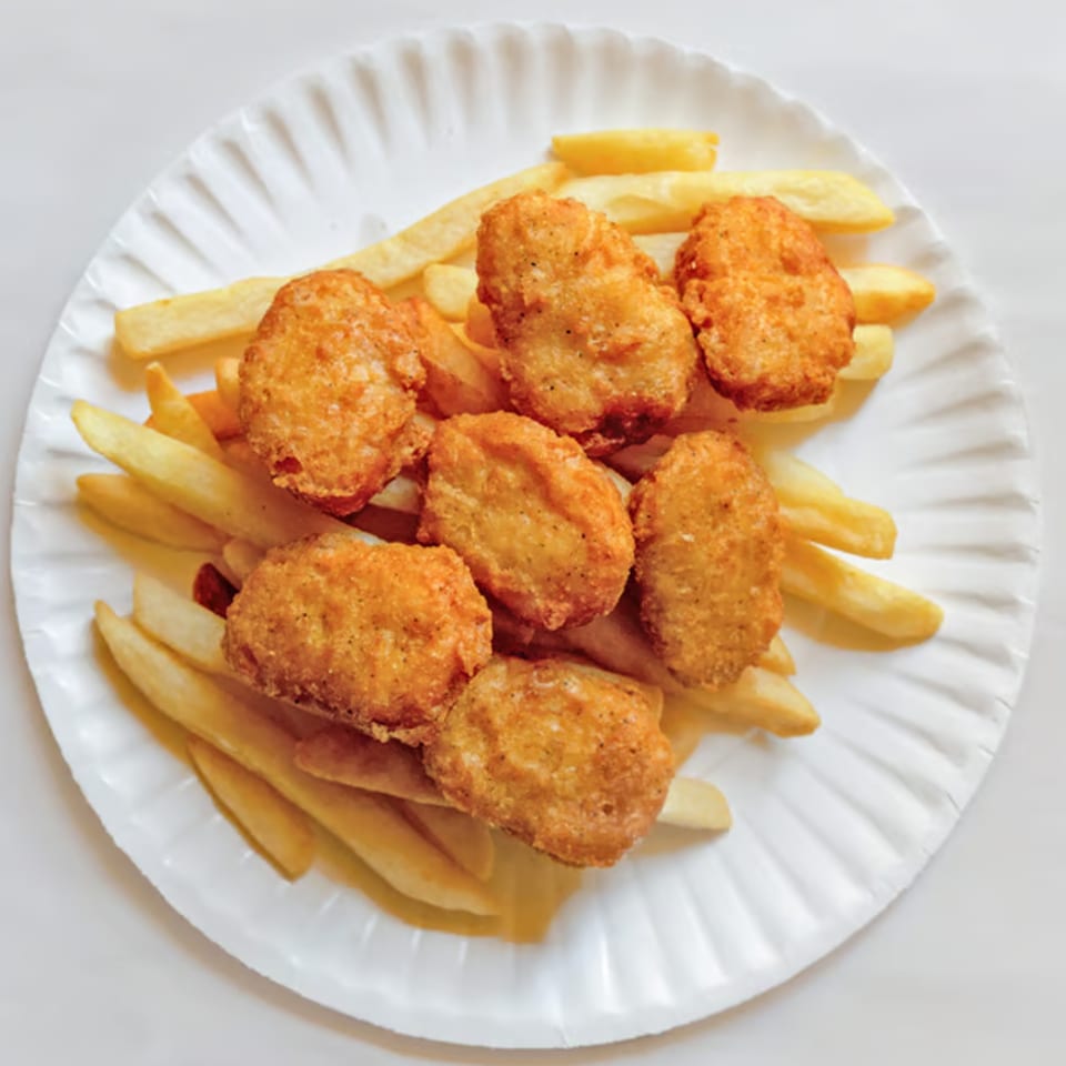 A white paper plate filled with golden-brown chicken nuggets and crispy french fries.