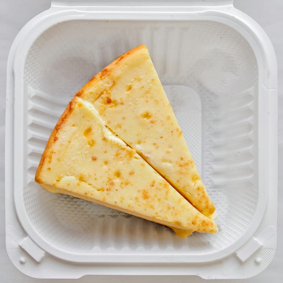Two slices of Massey's cheesy bread, golden brown and speckled, in a white takeout container.